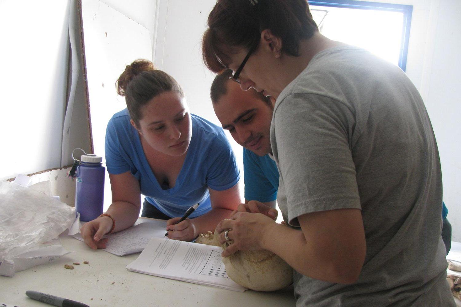 UNC students Jennifer Wright 和 Katelyn McEachern work with Albanian student Marlon to analyze skeletons in Albania.
