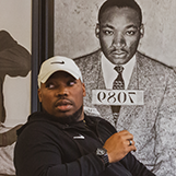 Rico Wint '08 sits in front of a photo of Martin Luther King Jr.