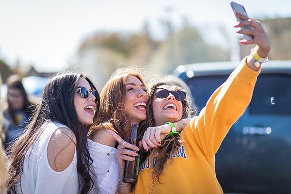 Girls holding a phone up taking a photo.